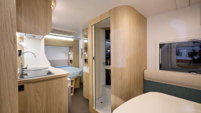 La Mancelle Fantaisy 440CL's interior has wooden furniture and a front dinette.  The kitchen sink is on the left hand side, opposite the shower.  The fixed bed is at the rear. 