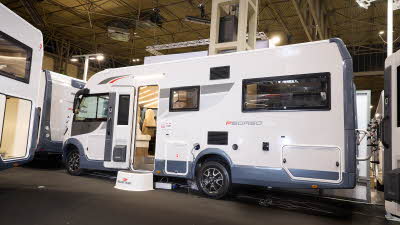 The Roller Team Pegaso 745 is white with blue trim and grey and red decals. There is a white step outside the open habitation door.