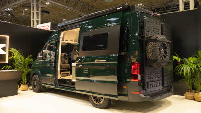 The Onyx Vans Summit 2.0 is dark green, its sliding door is open.  There is a spare wheel on the back of the vehicle.