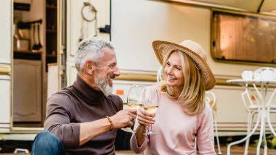 A couple toasting outside their outfit on holiday.
