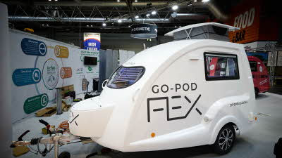 Going Go Pod Flex's exterior is white with its name emblazoned on the side in black.  It's pop top roof is open.