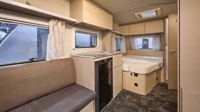 Weinsberg CaraCito 450 FU's interior is primarily wooden with two tone brown seating.  The fixed bed is to the rear.  There is a patterned carpet.