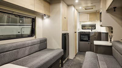 Interior of the Xplore XC DUO with grey sofas, wood accents and grey carpets.  The kitchen is at the end of the caravans.