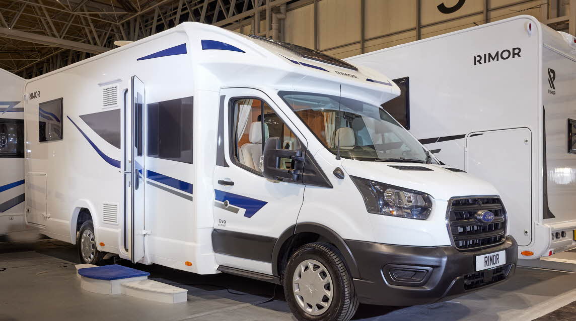 Rimor Evo 66 Plus has a predominately white exterior with blue graphics. The habitation door is open with a step to gain easy access. 