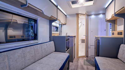 Bailey Discovery D4-2 interior, grey upholstery, pale wood cabinets, open skylight, wooden door which is open revealing the washroom