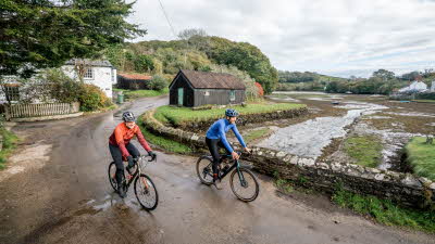 Two men cycling uphill on a rural road