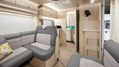 Auto-Trail F-Line F60 has two tone upholstery, with pale wooden furniture.  There is an extractor fan in the kitchen ceiling.  The floor has removable beige carpet. 